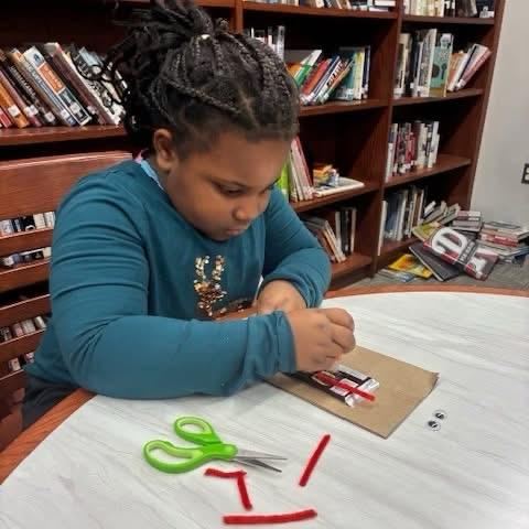 Young Butterfly focuses on a craft project in a library setting