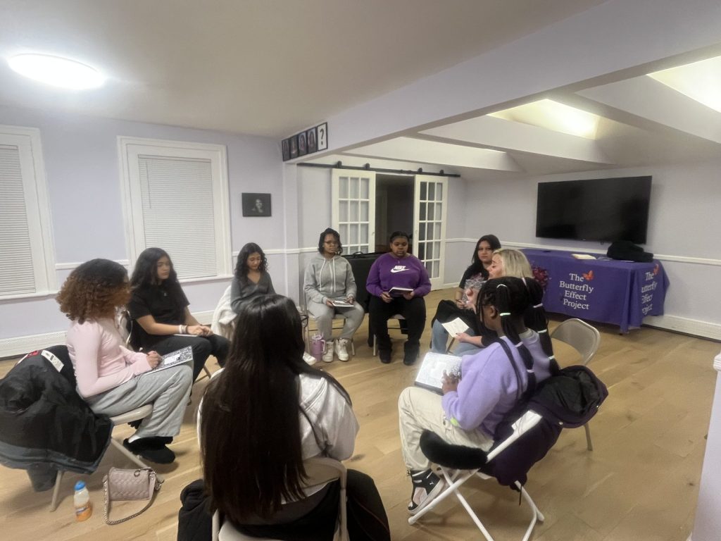 Youth and adults squeeze into a tight group huddle hug indoors.