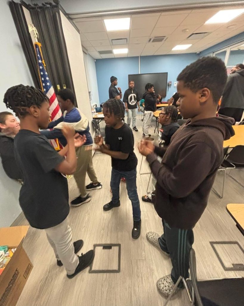 Youth and adults squeeze into a tight group huddle hug indoors.