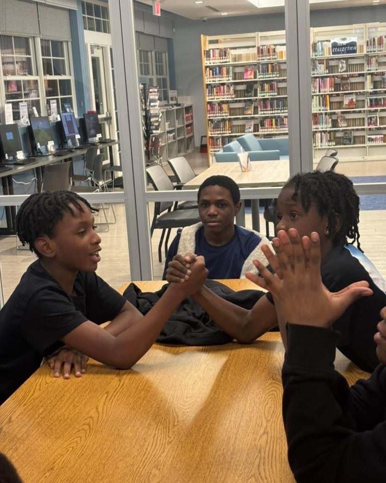 Two boys at a table smile mid high-five during a chapter activity.