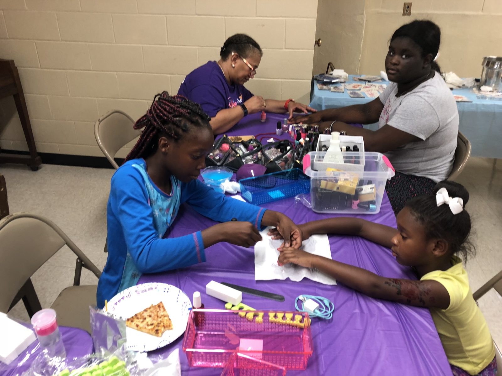 Young women sit in a circle of folding chairs in a bright room with Butterfly Effect table branding.