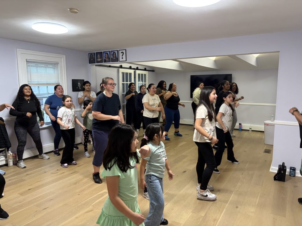 Youth practice on a dance studio floor while others watch.