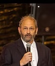 Andrew Torgove speaks into a microphone while wearing a navy blazer and white shirt.