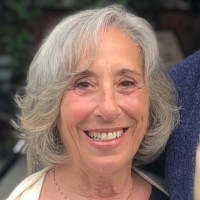 Stephanie McEvily smiles in an outdoor portrait with silver-grey hair.